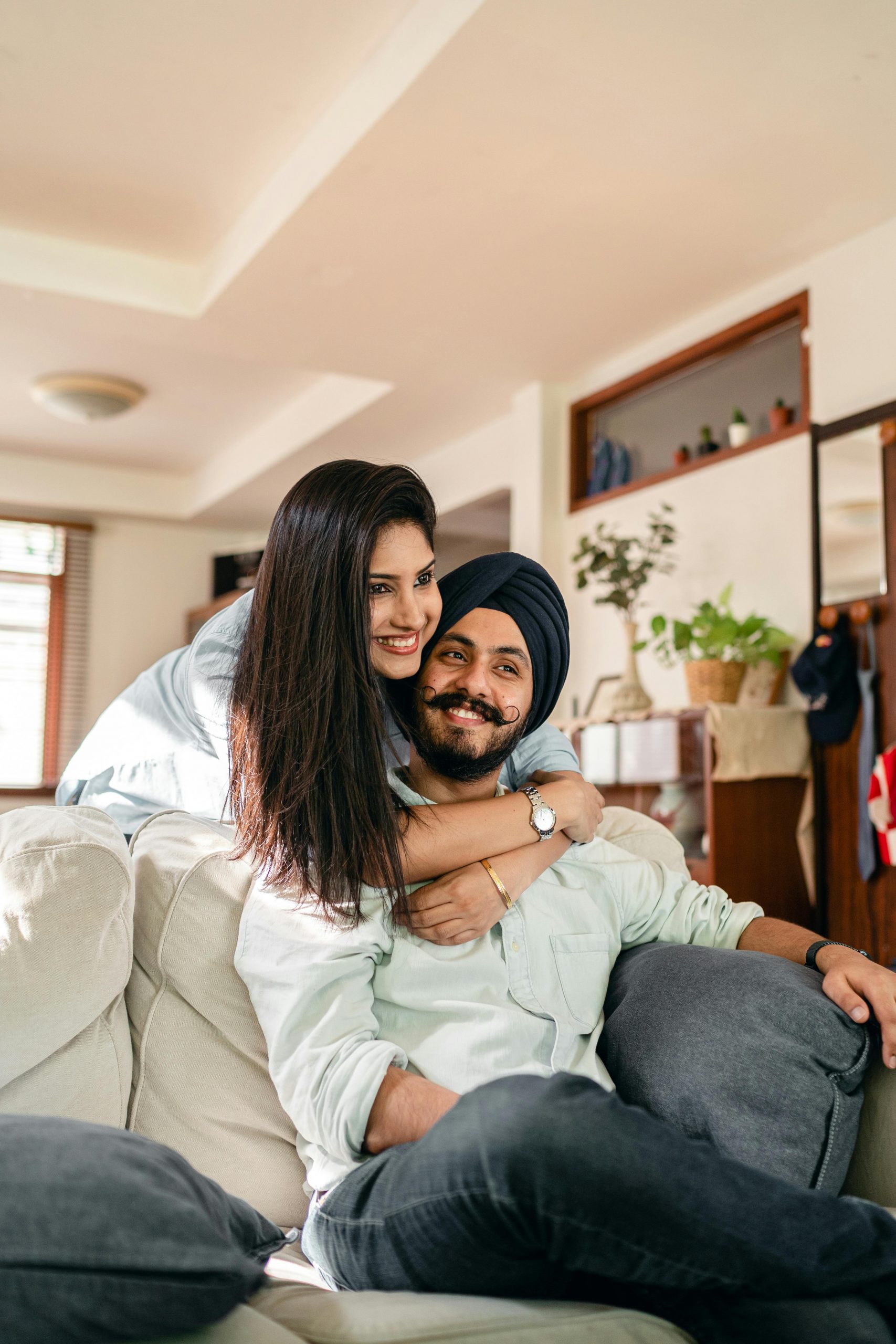 Warm and joyful couple embracing on a cozy sofa in their modern living room.