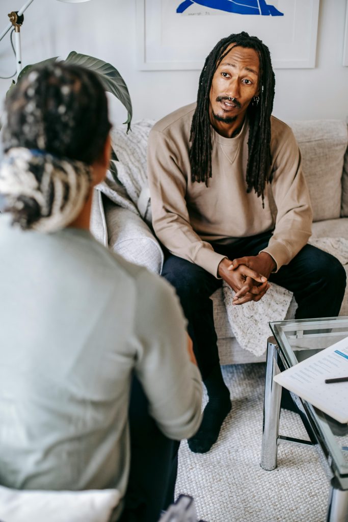 A patient and therapist discussing therapy sessions indoors on a comfortable couch.