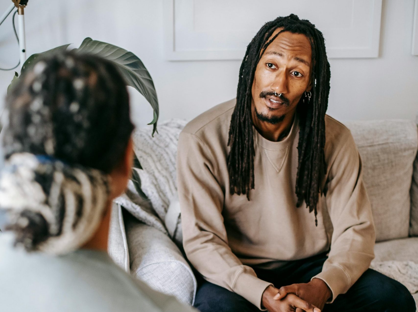 A patient and therapist discussing therapy sessions indoors on a comfortable couch.