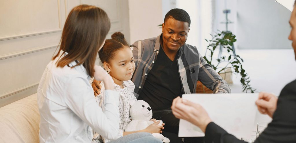 A family therapy session with a young girl, parents, and therapist discussing together.